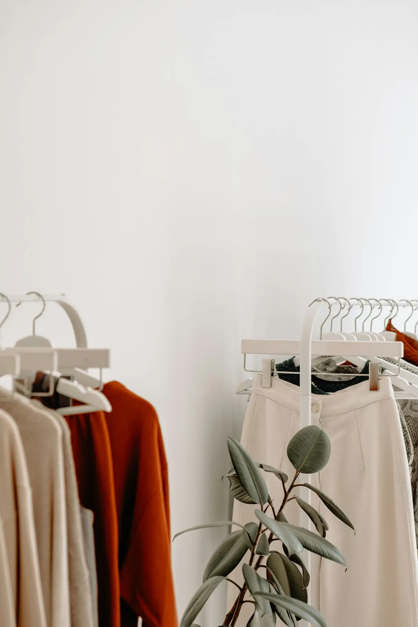 A neatly arranged clothing rack in neutral tones, representing the visual brand identity that ad creative needs to match.