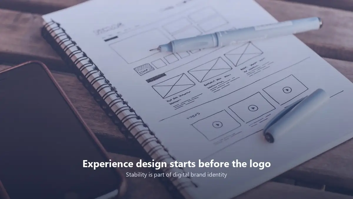 Mobile wireframe sketches on a desk, representing experience design and digital brand identity work.